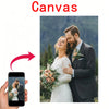 A couple embracing in wedding attire is displayed on a smartphone screen, suggesting custom photo canvas wall art.