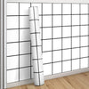 A roll of white grid peel-and-stick wallpaper mounted on a wall with a grid pattern.