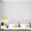 A bedroom featuring a white subway tile accent wall, a gray bed frame, and pillows with yellow accents.