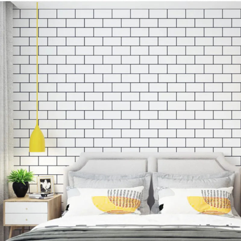 A bedroom featuring a white subway tile accent wall, a gray bed frame, and pillows with yellow accents.
