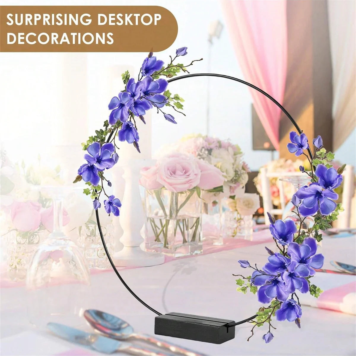 A black metal hoop centerpiece decorated with purple and pink flowers on a table.