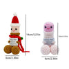 A handmade crochet figurine decoration of a male figure wearing a red outfit and a white hat.