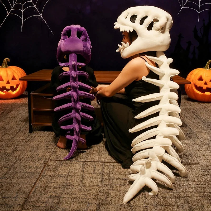 Une personne pose avec deux peluches squelettes de dinosaures réalistes, un violet et un blanc, sur fond sombre.