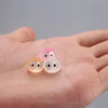 Three glow-in-the-dark resin ghost tree elves in pink and translucent colors resting on a hand.