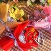 A bouquet of handmade crochet yarn flowers in yellow, pink, and red are displayed in tissue paper.