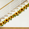 A staircase decorated with a garland of yellow sunflowers and green leaves.