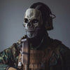 Una persona vistiendo una máscara facial de silicona táctica con diseño de calavera y ropa de camuflaje militar.
