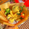 A bouquet of handmade crochet yarn flowers in yellow and green nestled in orange paper.