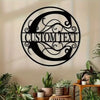 A black metal wall sign with custom text carved into an ornate circular design mounted on a light-colored wall.