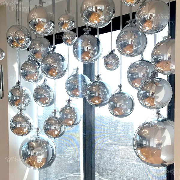 A collection of twelve metallic silver foil balloons hanging in a vertical display.