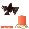A soft red candle in a glass jar sits on a gold wire stand next to dark chocolate dye blocks.