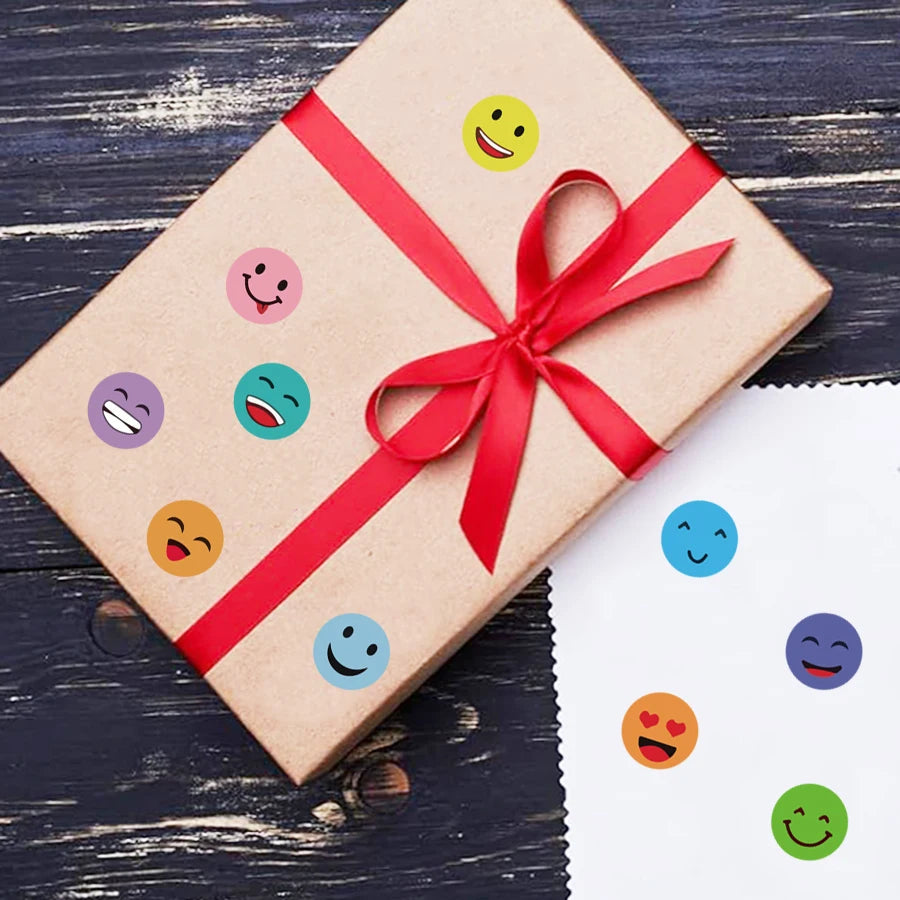 A brown gift box tied with a red ribbon decorated with colorful round smiling face stickers.