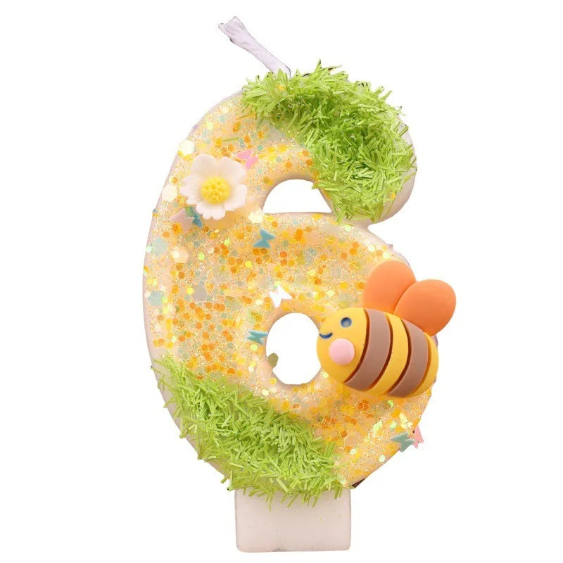 A golden number six candle decorated with green moss and a bee face