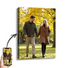 A framed canvas wall art featuring a smiling couple outdoors in autumn foliage.