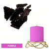 A purple candle in a gold wire holder next to black dye blocks.