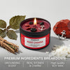 A dark red candle jar labeled Evoduck Root Chakra with a flame, surrounded by dried leaves and a red stone.