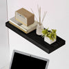 A dark wood floating shelf displaying a rectangular textured box, a stack of books, and a small potted plant with dried stick
