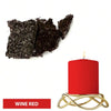A red wine colored candle in a gold holder next to dark dye blocks.