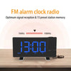 A black projection alarm clock with a large blue LED display showing 13:00 and FM radio tuning options.