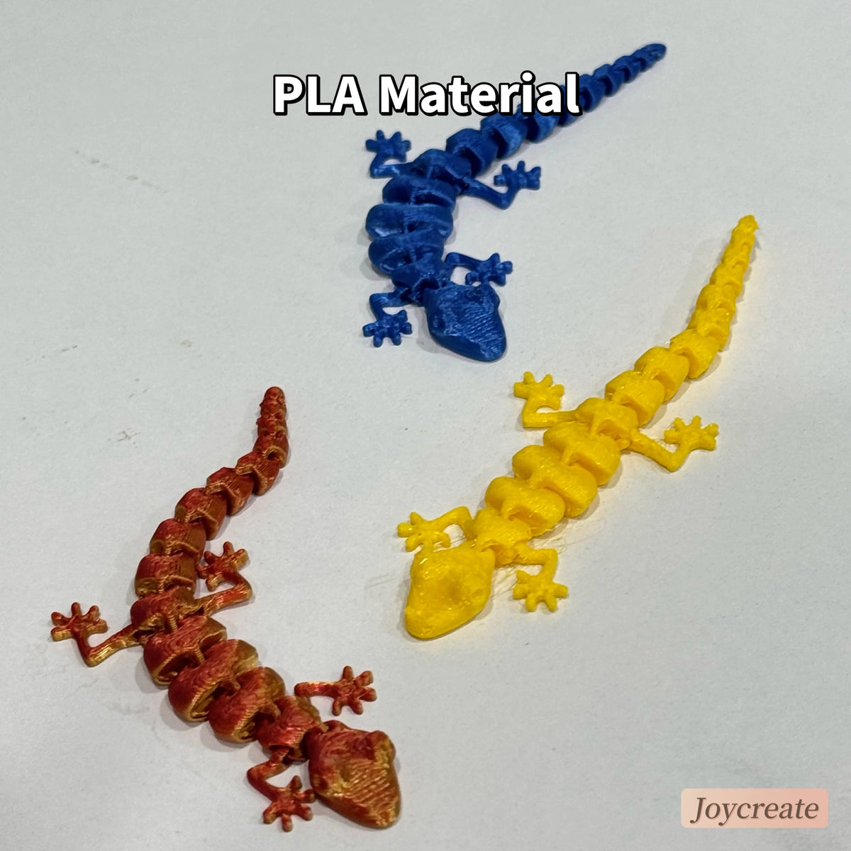 Three 3D printed articulated lizard figurines in blue, yellow, and reddish-orange.