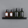 Three dark glass bottles of liquid soap or lotion displayed on a modern matte black wall shelf.