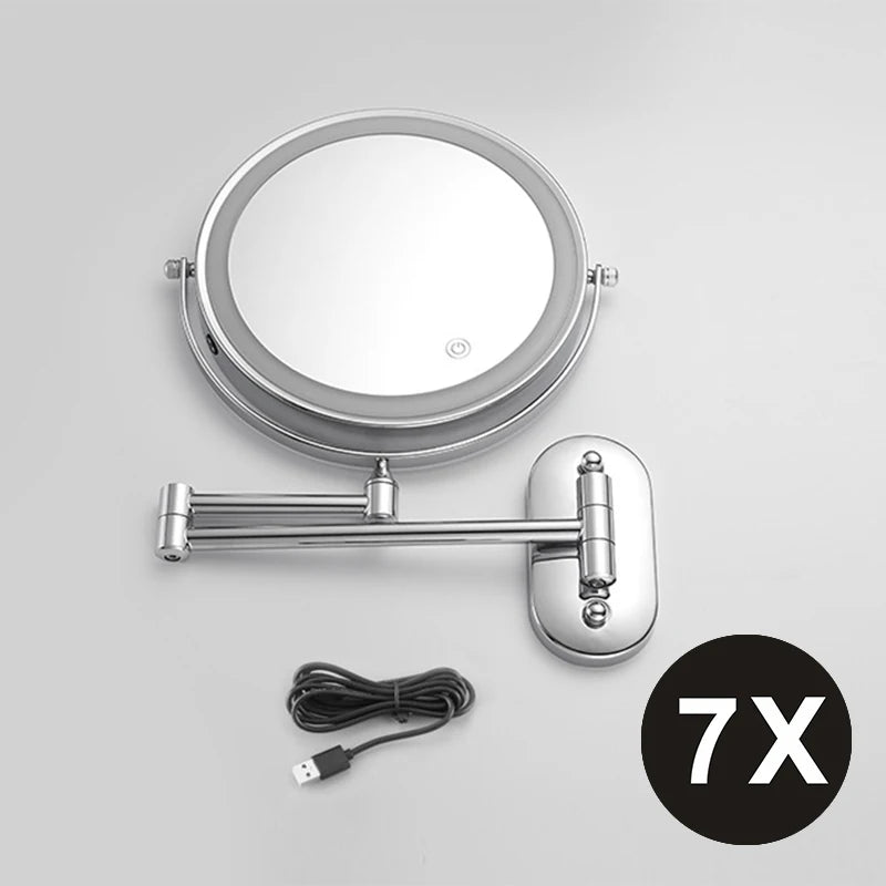 A round, silver-framed magnifying makeup mirror with a handle and USB charging cable.