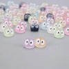 A collection of glow-in-the-dark resin ghost tree elves in various pastel colors arranged on a gray surface.