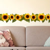 A decorative garland of yellow sunflowers with green leaves displayed above a beige sofa.