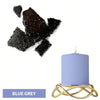 A blue grey candle in a gold wire holder next to black and grey dye blocks.