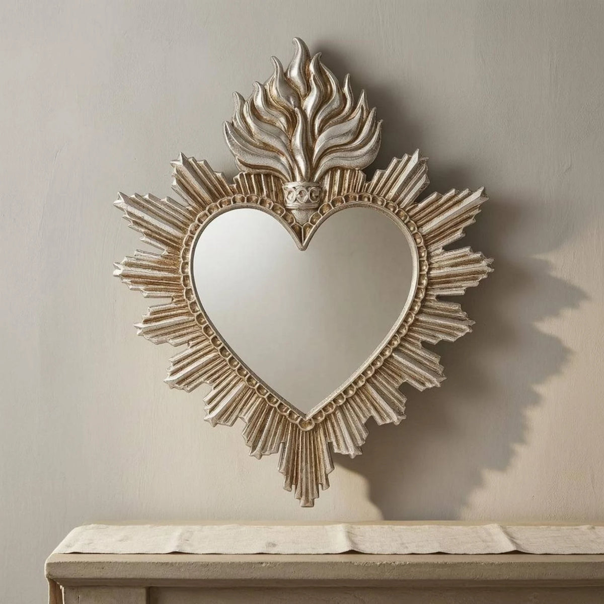 Ornate flame wall mirror with a heart shape framed by radiating leaves and textured edges.