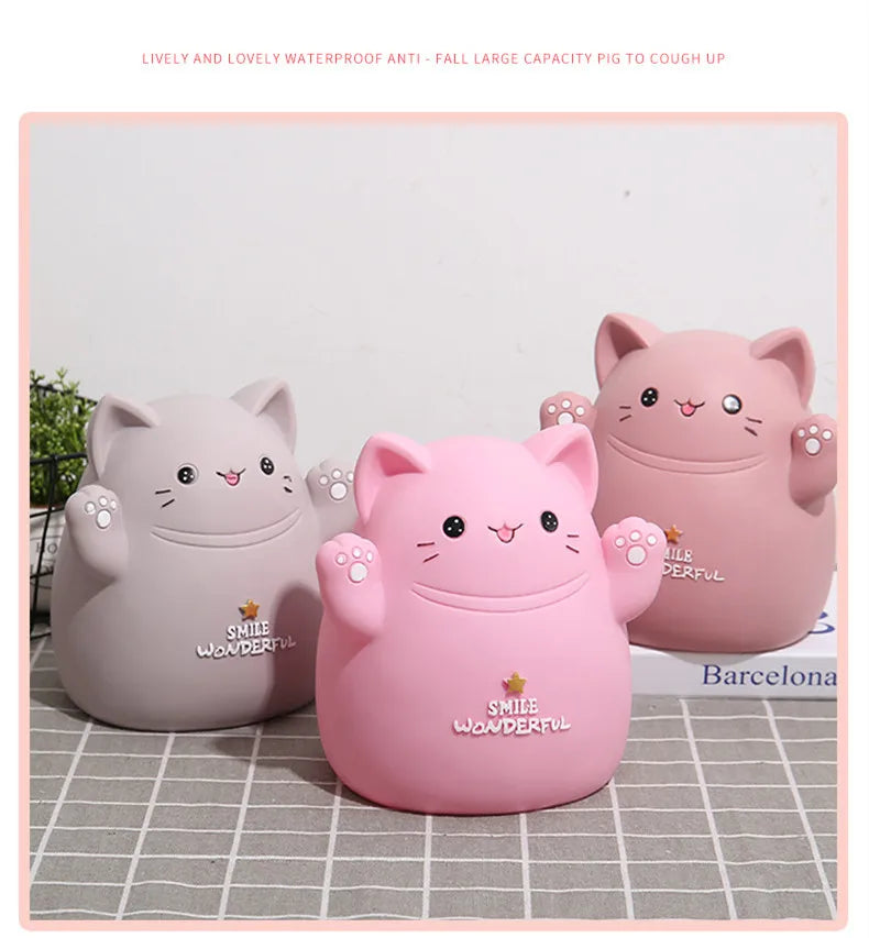 A pink cartoon cat piggy bank with a smiling face sitting on a light gray surface.