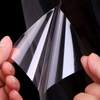 A hand holds a clear, flexible film sticker, demonstrating its self-adhesive properties.