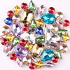 A mix of silver claw setting glass rhinestones in jelly candy AB colors scattered on a white background.