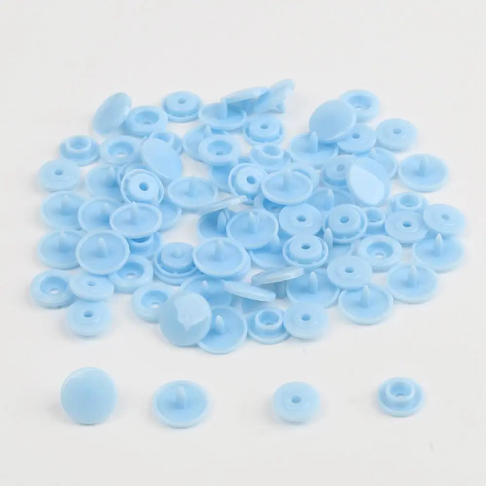 A pile of assorted light blue snap buttons, measuring 12mm and 10.5mm, for crafting.
