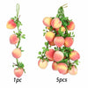 A sprig of artificial pink and yellow fruit, resembling apples or peaches, used for decoration.