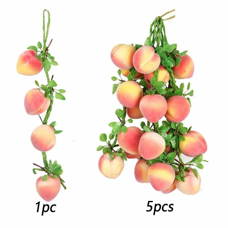 A sprig of artificial pink and yellow fruit, resembling apples or peaches, used for decoration.