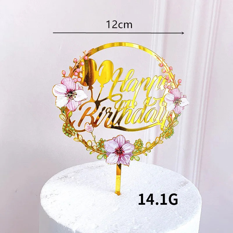 Rose gold acrylic happy birthday cake topper featuring floral accents on a white cake.