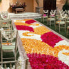 A long aisle decorated with silk rose petals in shades of pink, orange, and white for a wedding ceremony.