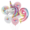 Un ballon en feuille en forme de licorne blanche avec une crinière et une corne arc-en-ciel, entouré de ballons roses et mult