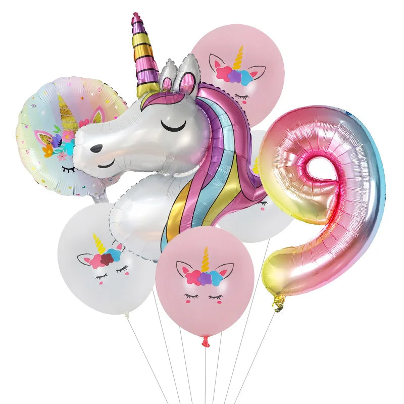 Un ballon en feuille en forme de licorne blanche avec une crinière et une corne arc-en-ciel, entouré de ballons roses et mult