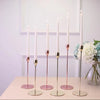 A set of tall, slender iron candles with pink accents displayed on a light wooden surface.