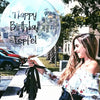 A young woman smiles while holding a large clear balloon with the text Happy Birthday Esfel to celebrate an event.