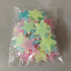 A clear plastic bag filled with a 50-pack of glow-in-the-dark star wall stickers in various pastel colors like pink, blue, an