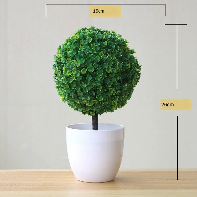 Artificial bonsai tree in a white pot with dense green foliage, shown against a light background.