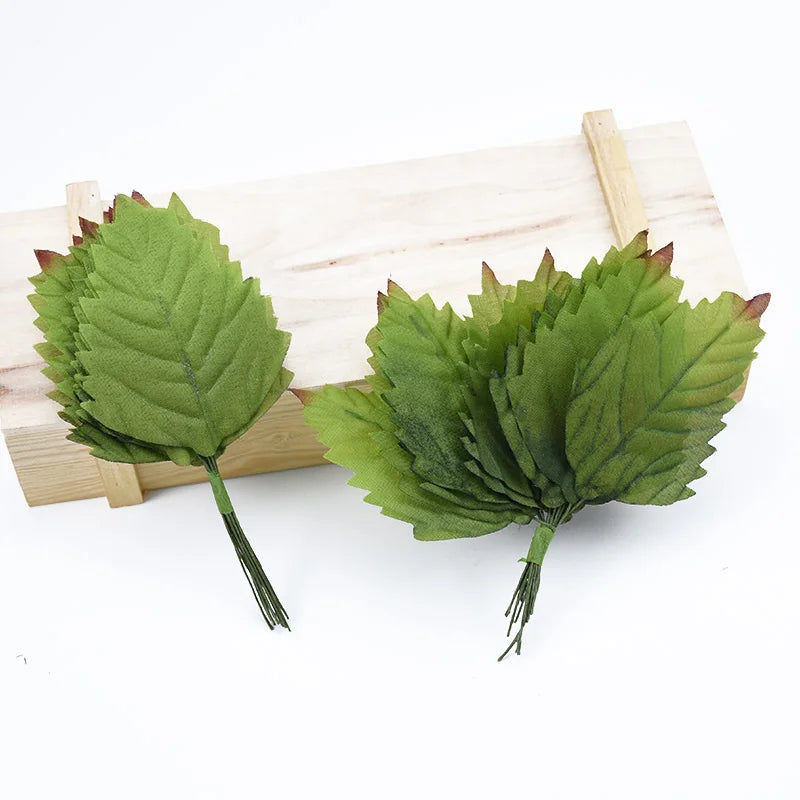 A set of twelve silk leaf artificial plant stems used for vases, displayed on a wooden board.