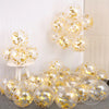 Un grupo de globos transparentes llenos de confeti dorado y adornos de papel de oro