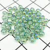 A pile of clear green and blue iridescent acrylic round beads for jewelry making