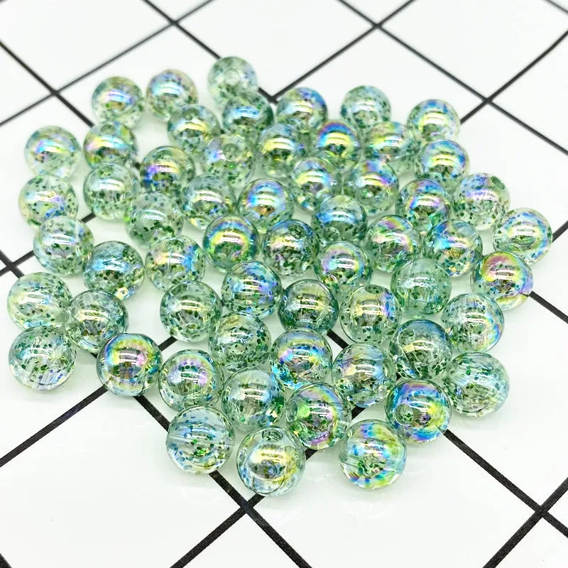 A pile of clear green and blue iridescent acrylic round beads for jewelry making