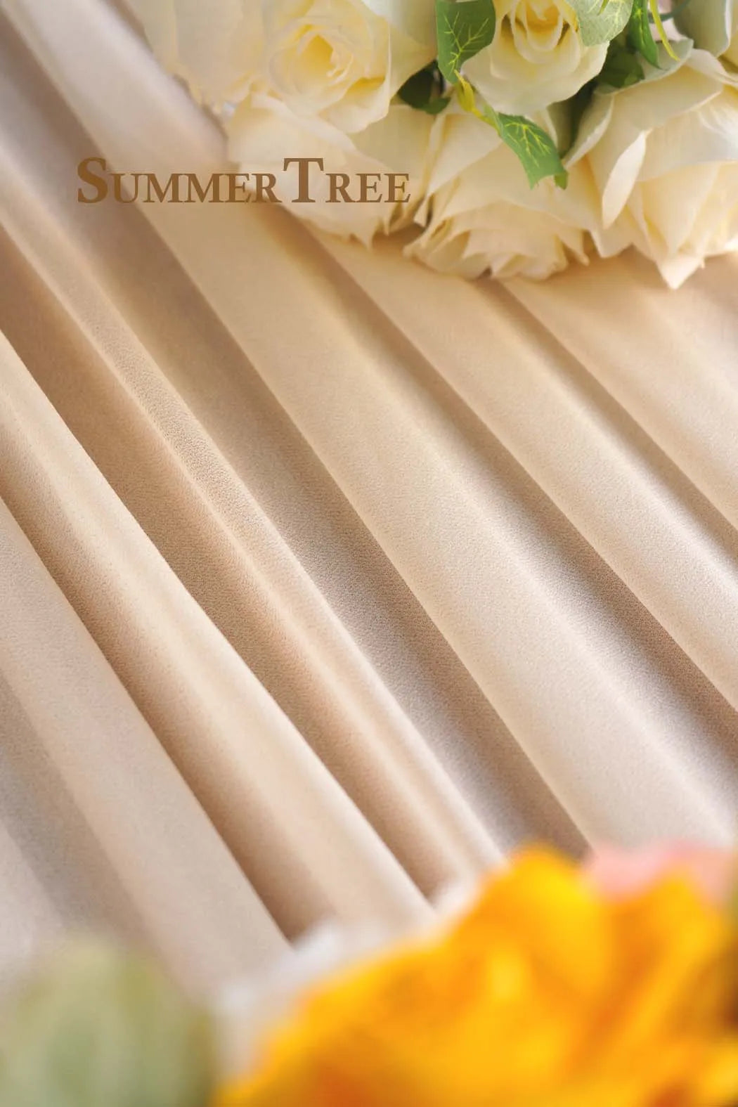 Soft beige sheer chiffon fabric draped with white roses and yellow floral accents.