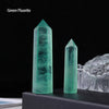 A tall, green fluorite crystal point prism displayed in a clear holder against a dark background.